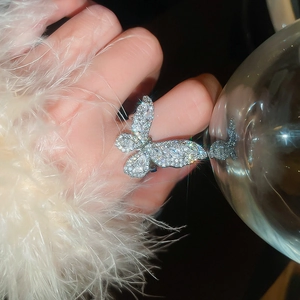 Close-up of a sparkling zircon butterfly ring worn on hand with elegant feathers