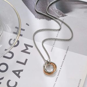 Minimalist interlocked triple ring necklace in silver and rose gold on a magazine
