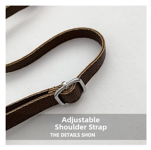 Detail of adjustable shoulder strap with silver buckle on brown lychee leather bucket bag