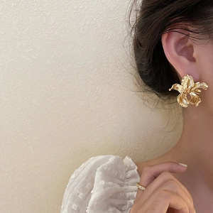 Detailed view of irregular golden 3D flower earrings with vintage crinkled texture