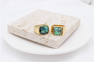 Close-up of golden shell rings on stone display showing colorful abalone textures
