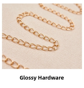 Detailed close-up of a polished gold metal chain strap on a light textured fabric background