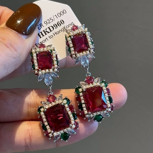 Detailed close-up of vintage gold earrings with red ruby-style stones and pearl border