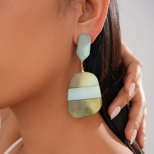 Detailed close-up of bohemian acetate oval earrings with green marble texture worn on ear