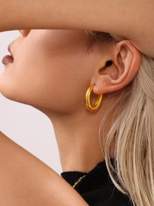 Close-up of elegant gold plated oval hoop earring worn on model earlobe
