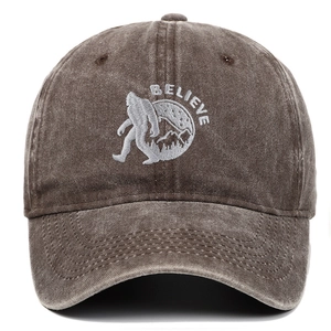 Detail of white Bigfoot embroidery and Believe text on brown washed cotton baseball cap