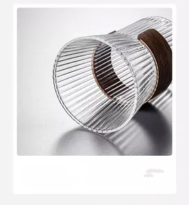 Close-up of ribbed glass cup featuring a wooden heat insulation sleeve and smooth rim