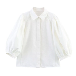 Chemise blanche à manches bouffantes et col polo sur fond blanc pour un look chic
