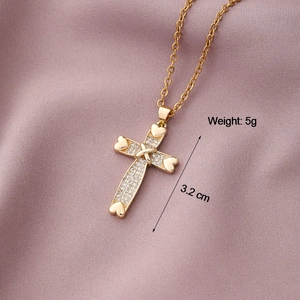 Gold cross pendant necklace with heart details and white zircons on purple silk fabric