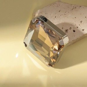 Macro shot of large square champagne crystal ring with a gold metal claw setting on a rock