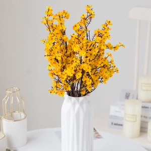 Macro shot of artificial yellow gypsophila bouquet in a white textured ceramic vase