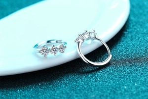 Macro shot of silver hoop earrings featuring three sparkling round-cut moissanite stones