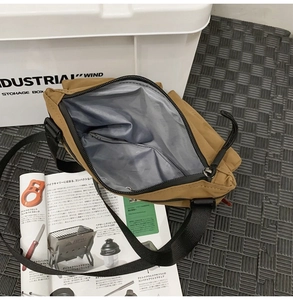 Detail view of khaki nylon messenger bag interior with silver lining and zipper