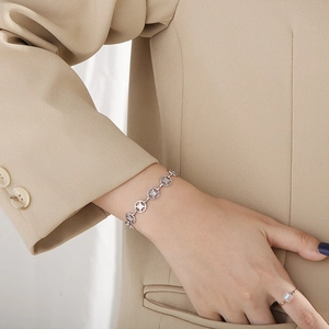 Close-up of minimalist silver bracelet with hollow circular links worn on a wrist
