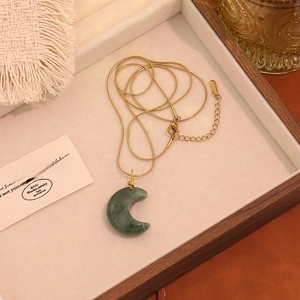Dettaglio della collana a mezzaluna con pietra verde e piccola croce dorata
