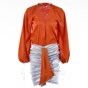 Dettaglio della camicia in seta arancione con scollo a V e minigonna a balze azzurra