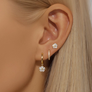 Close-up of a gold floral earring set with clear zircon on woman's earlobe