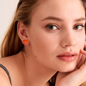 Vintage orange enamel heart stud earrings with gold trim worn by a model in profile