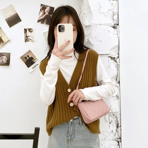 Pink quilted shoulder bag with chain strap styled on model with a brown vest