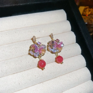 Detail of butterfly drop earrings with pink accents and red beads on velvet display
