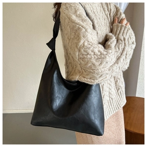 Detail of black large-capacity shoulder bag featuring a stylish knotted strap design