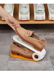 Adjustable two-tier shoe organizer in white and orange plastic showing folding mechanism