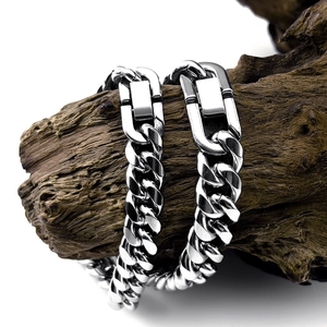 Detailed view of silver stainless steel Cuban chain bracelet with U-buckle on dark wood