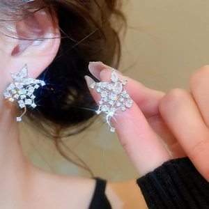 Détail macro de boucles d'oreilles étoiles en argent avec zircons sur un mannequin