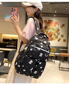 Detail of black bear print backpack featuring multiple zipper pockets and large capacity