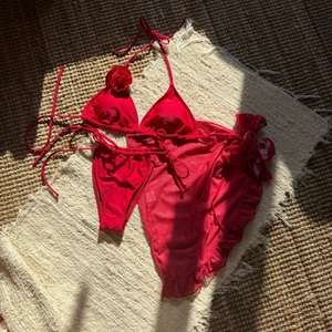 Detail of red bikini set with 3D rose accent and matching ruffled mesh sarong