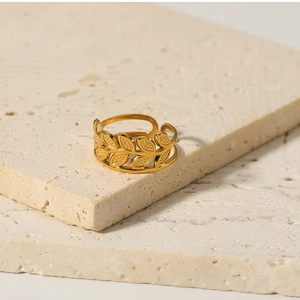 Detailed shot of 18k gold leaf ring on white stone, showing olive branch design
