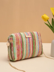 Detail of colorful woven straw bag with gold metal chain and zipper in summer setting