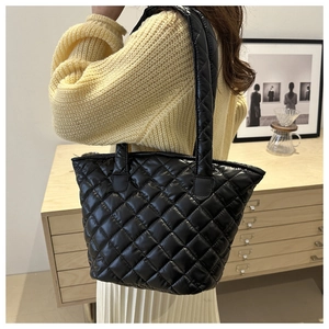 Détail d'un sac cabas noir matelassé montrant sa texture rembourrée et sa grande bandoulière