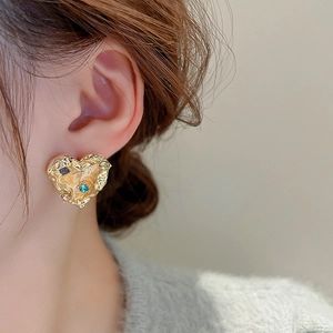 Close-up of heart-shaped gold studs with irregular lava texture and colorful zircons