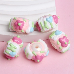 Macro shot of colorful resin beads with cream cake and flower designs on a white stone