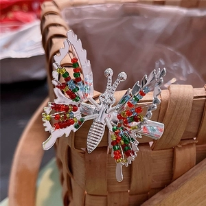 Silver metal moving butterfly hair clip with colorful beads on bamboo basket background