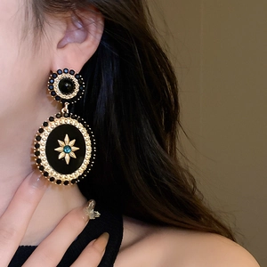 Macro shot of vintage baroque style oval earrings featuring gold star and blue gemstone