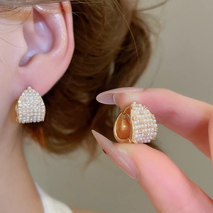 Detail of elegant gold hoop earrings with micro-inlaid pearls and sparkling cubic zirconia