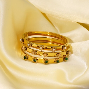 Three gold stainless steel bracelets with colorful daisy floral motifs on silk fabric