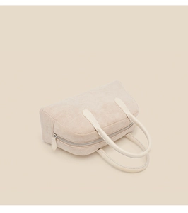 Top view of beige suede bowling bag with leather handles and metallic zipper detail