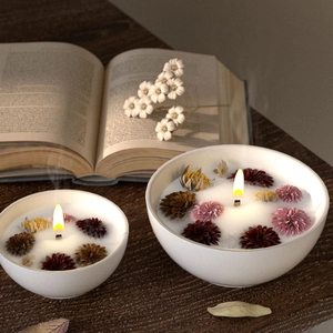 Artistic set of two white ceramic candle bowls with dried flowers on dark wood table