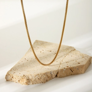 Minimalist 18k gold plated stainless steel mesh chain necklace on a stone pedestal