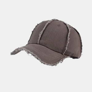 Detailed macro view of distressed raw edges and frayed seams on dark grey cotton baseball cap