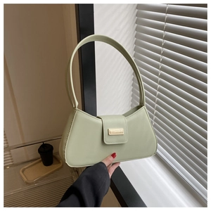 Detail of the light green baguette bag featuring smooth texture and a gold metal clasp