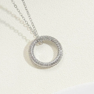 Detail of silver paved circle pendant with clear zircons on delicate cable chain