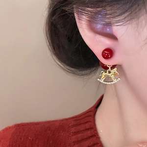 Boucles d'oreilles perles rouges avec pendentif cheval à bascule doré sur le mannequin