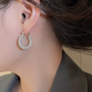 Close-up of silver U-shaped hoop earrings with cubic zirconia on woman's ear