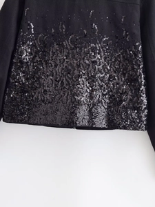Detailed view of shimmering black sequins with a gradient effect on the jacket hemline