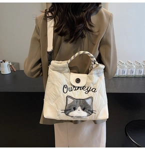 Detailed back view of white quilted tote bag with cat embroidery and woven handle