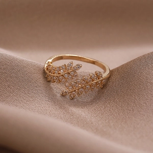 Elegant gold leaf ring with cubic zirconia accents on a champagne silk background